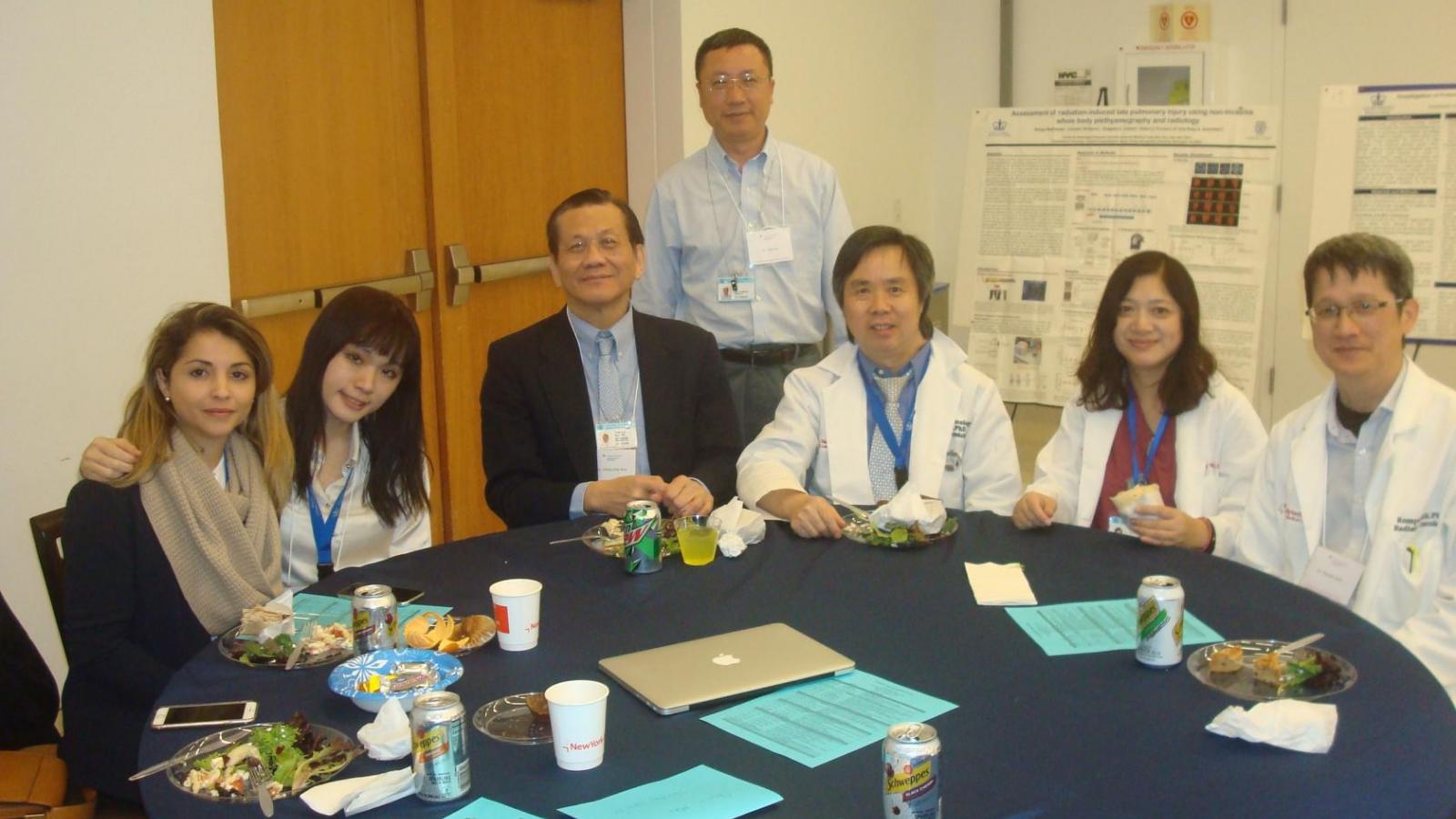 6 doctors sitting at table with one standing and posing for picture