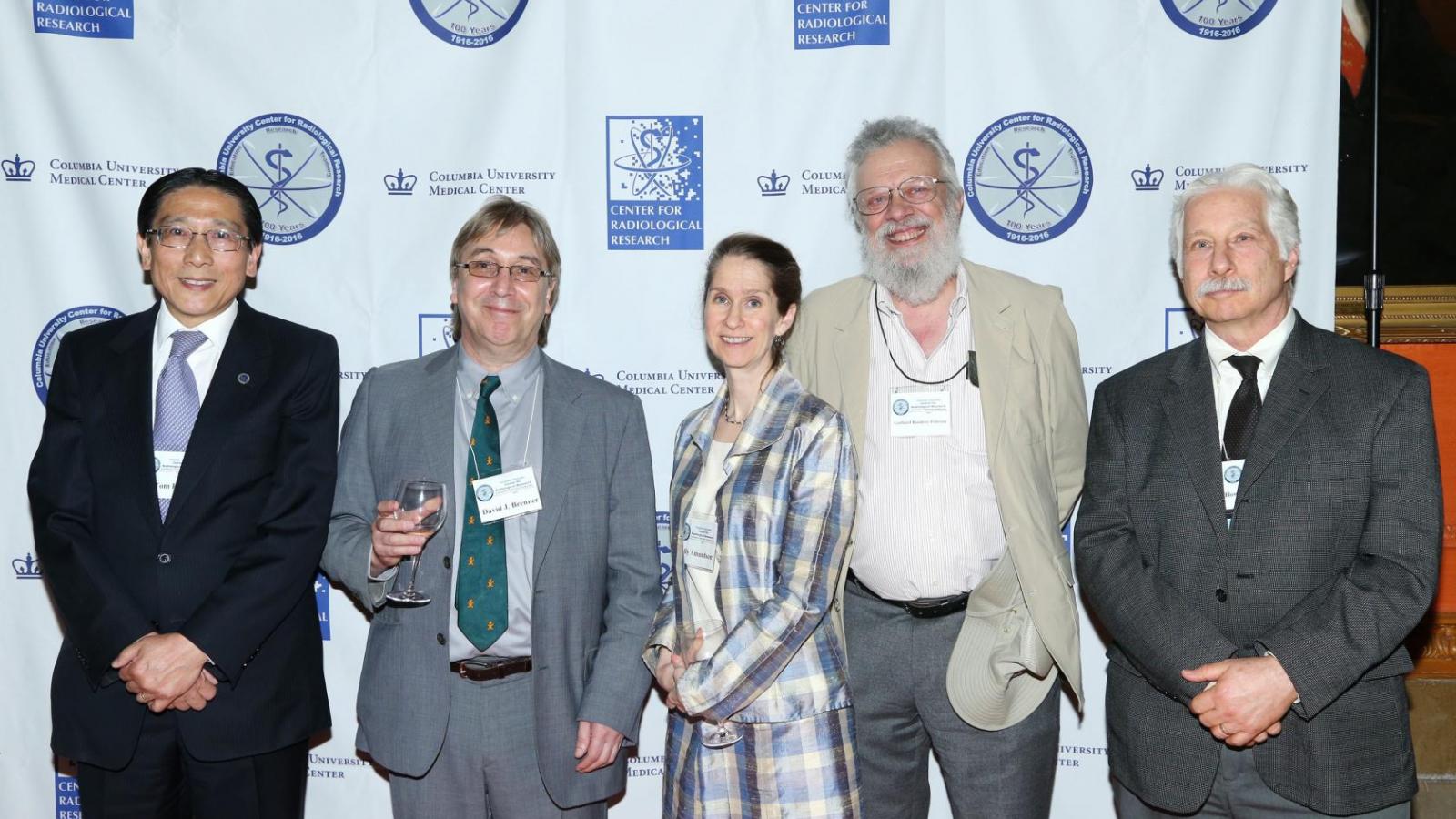 Five people standing posing for picture in front of backdrop with university and center for radiological research logos