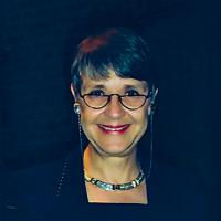 Woman with short hair, glasses and dark dress headshot